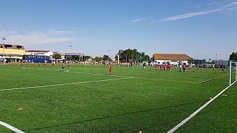 Youth players take part in football drills on an artificial turf training pitch.