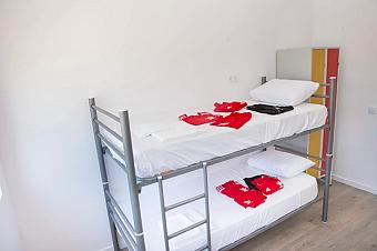 Bright bunk-bed room with white bedding and folded training camp sportswear.