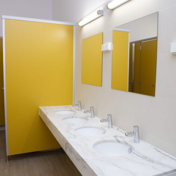 Modern shared bathroom with four sinks, mirrors, and yellow partitions.