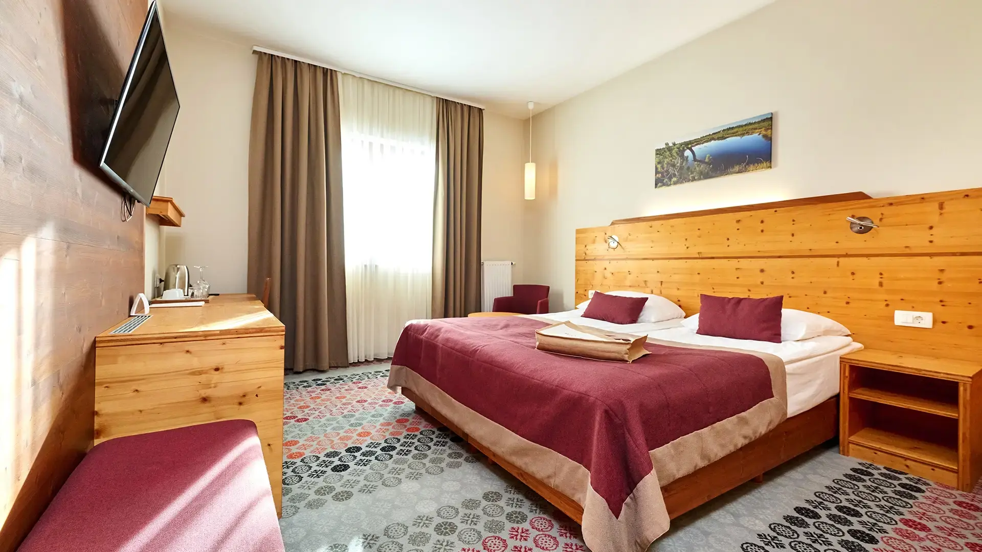 Bright double room with desk, TV and window seating area.