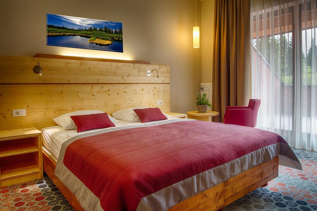 Double room with wooden furniture, red bedding and a large window.