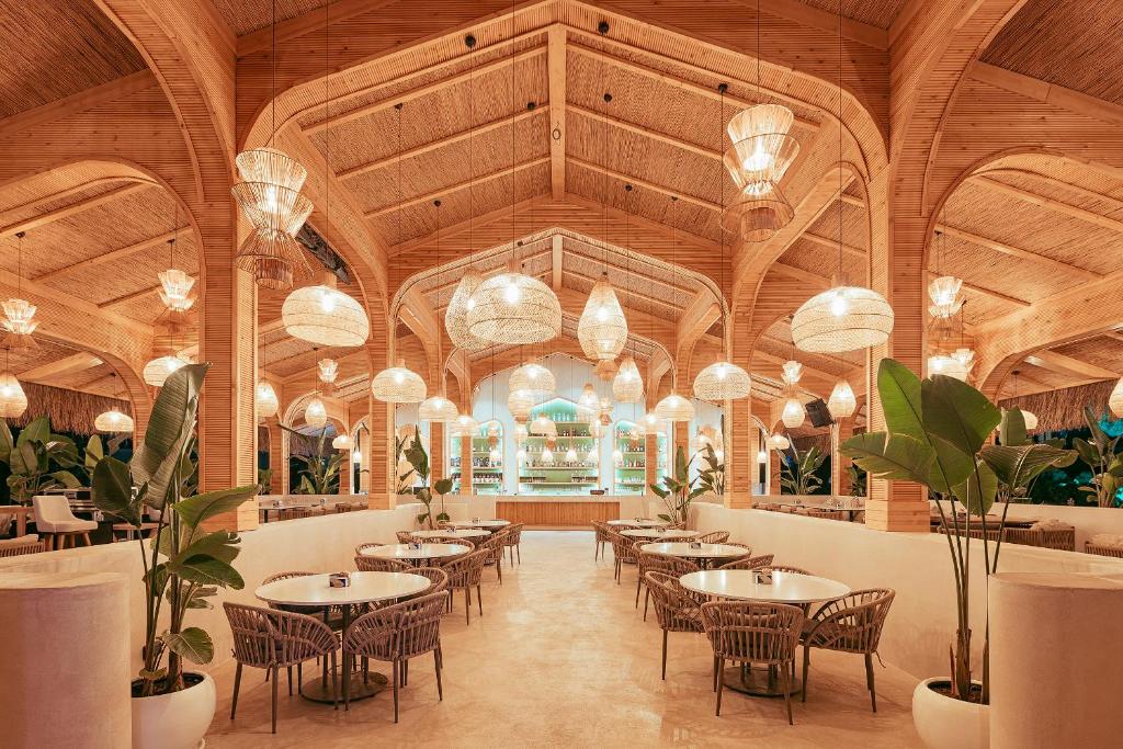 Stilvolle Bar- und Loungefläche mit warmer Holzarchitektur, geflochtenen Hängeleuchten und tropischen Pflanzen.