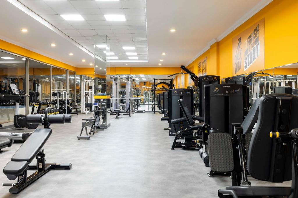 Weitwinkelansicht des Fitnessraums mit Bänken, Gewichten und Kraftgeräten.
