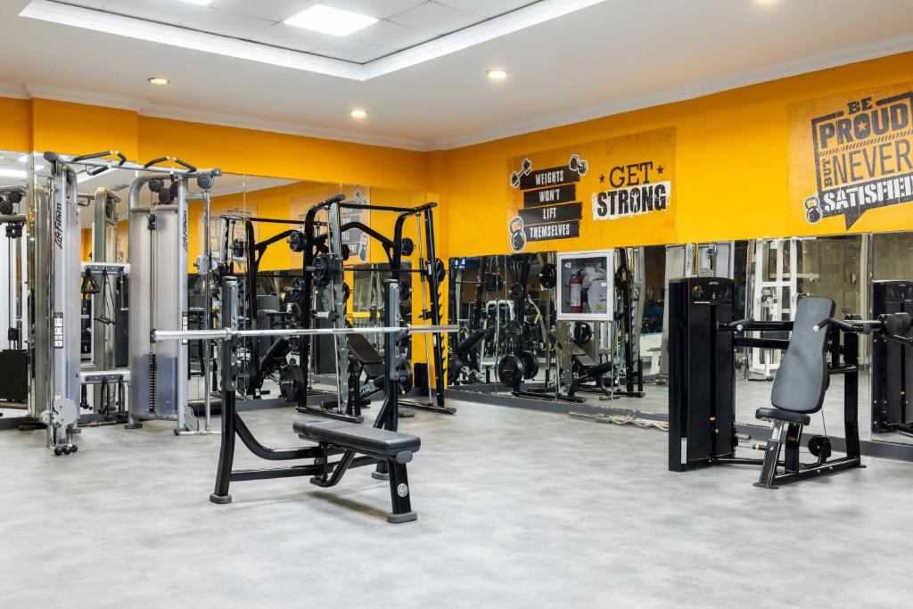 Fitnessbereich mit Kabelstationen, Bank und Spiegelwand.
