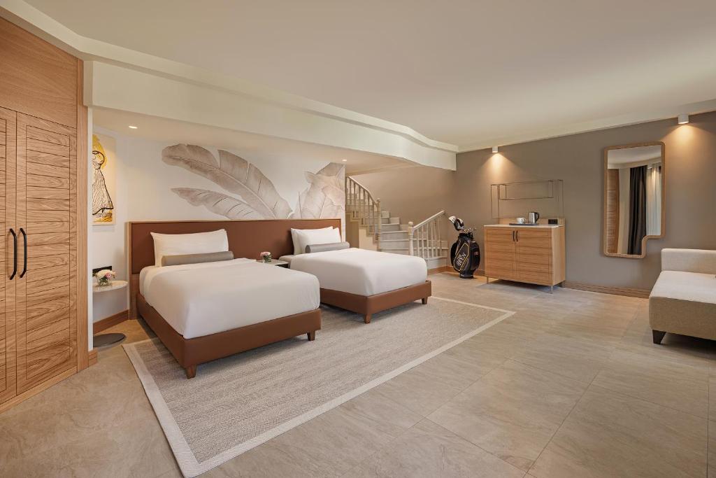 Geräumiges Gästezimmer mit zwei Betten, Sitzecke, Treppe und golfbezogener Dekoration.