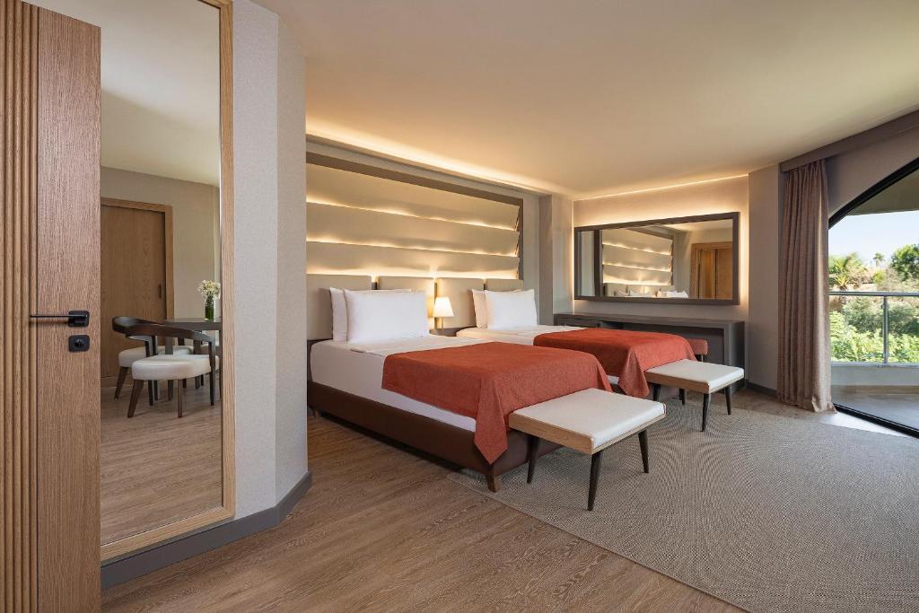 Geräumiges Zweibettzimmer mit Sitzbereich, Arbeitstisch und Zugang zum Balkon.