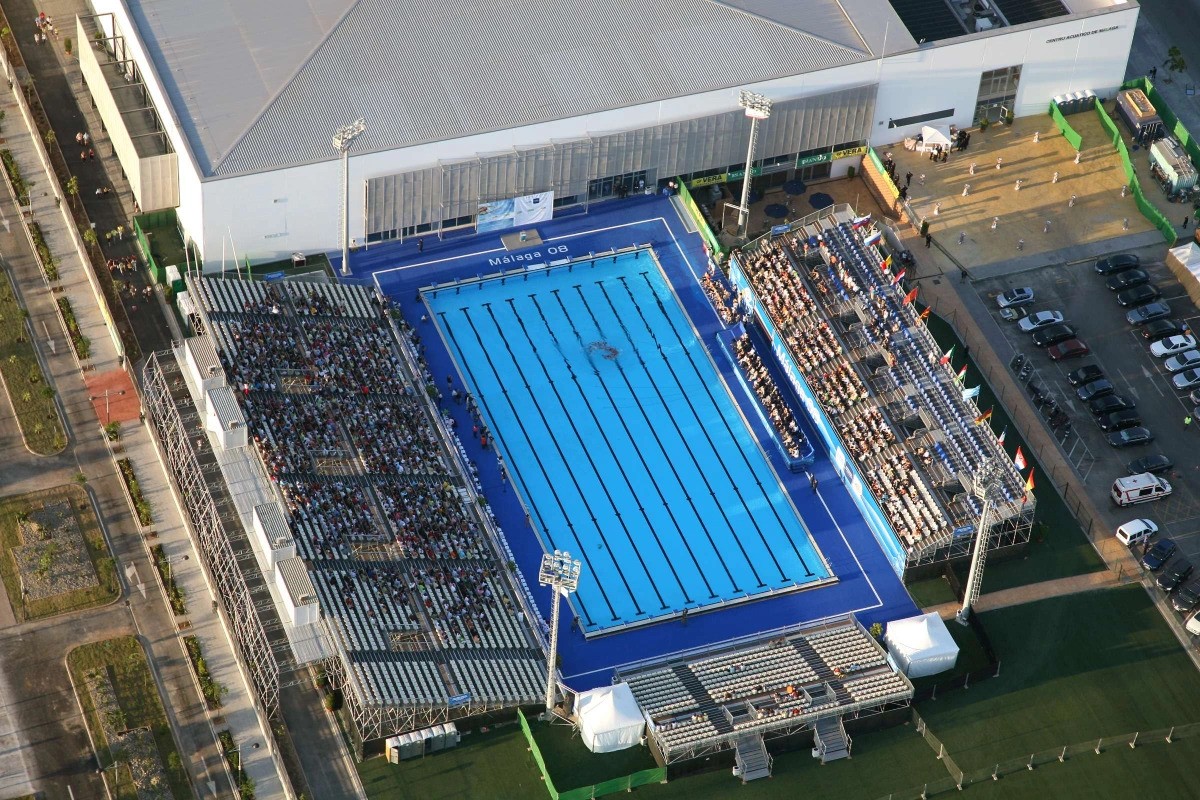 Aerial view of an outdoor competition pool with grandstands beside the venue.