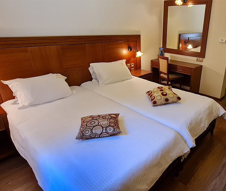 Twin room with wooden headboard, desk and two single beds.