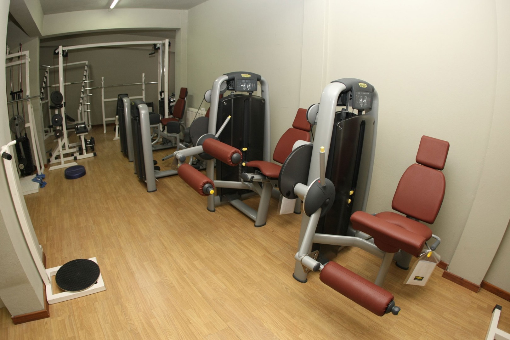 Compact gym with strength machines, benches and free-weight equipment.