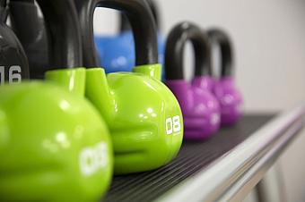 Close-up of colorful kettlebells lined up on rack in fitness area