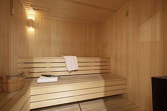 Wooden sauna room with benches, towel, and bucket
