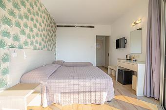 Bright hotel room with twin beds, pastel wallpaper, and modern furnishings