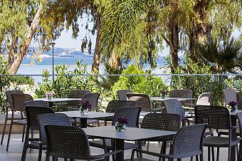 Outdoor dining area surrounded by greenery with tables overlooking the sea