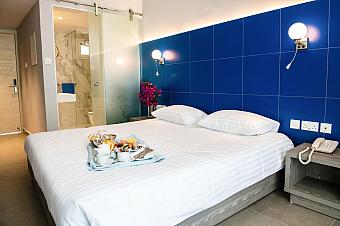 Cozy room with double bed, blue wall, and breakfast tray beside a marble bathroom entrance