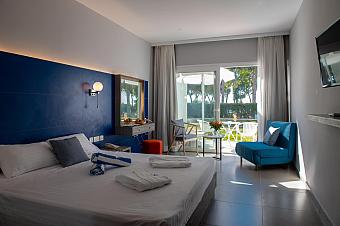 Modern hotel room with blue feature wall, white bed linens, and terrace view