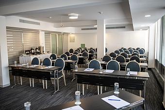 Bright meeting room with blue chairs, notepads, and glasses arranged for a team or training seminar