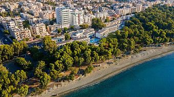 Aerial view of beachfront hotel complex surrounded by trees and city buildings near the coastline