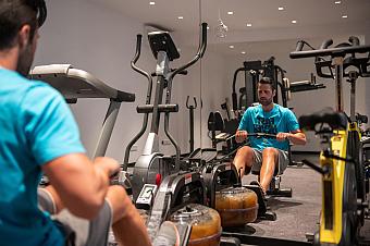 Athlete exercising on rowing machine in hotel gym with multiple fitness machines