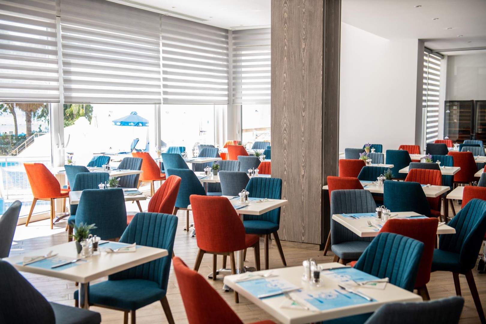 Modern indoor dining area with colorful blue and orange chairs arranged around square tables
