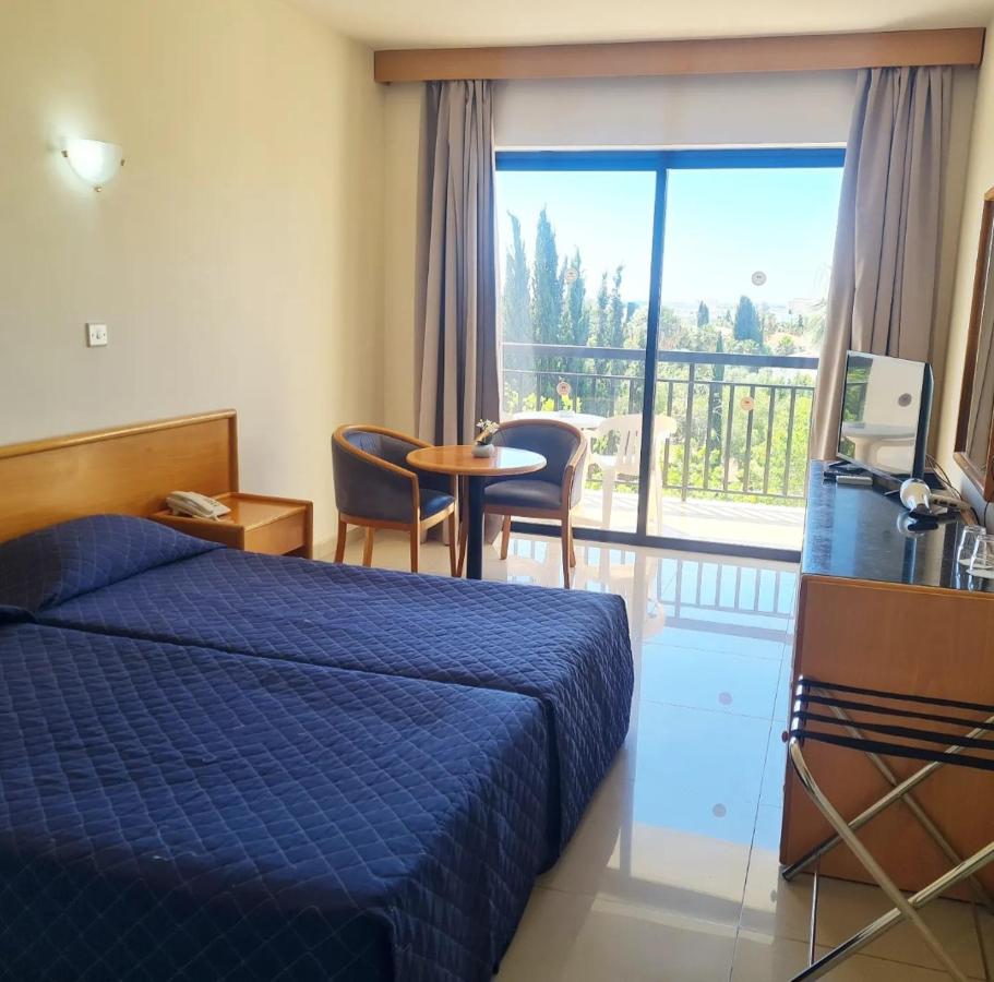 Twin guest room with balcony, TV, desk and seating area.