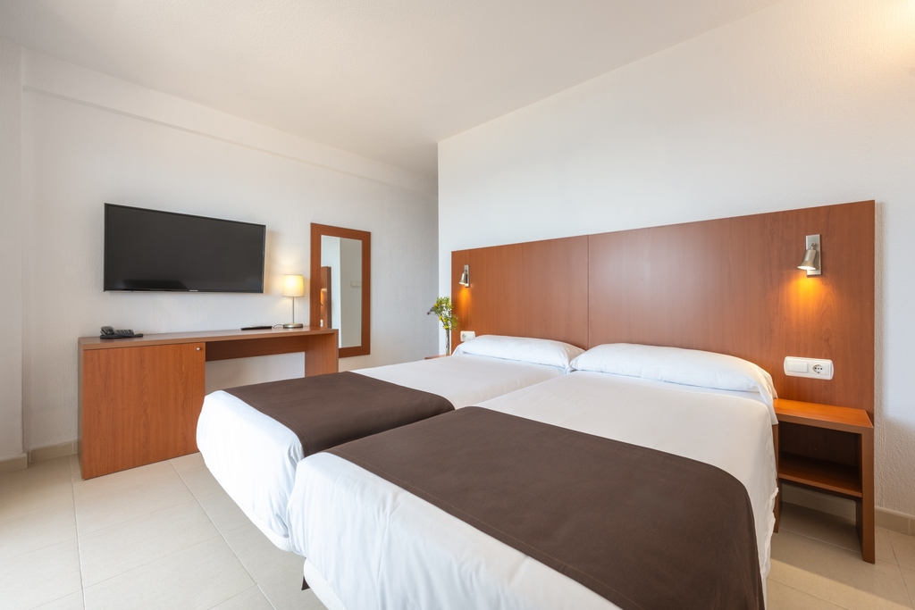 Twin room with two single beds, desk, TV and mirror.