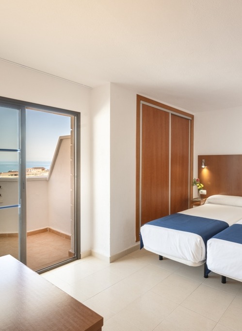 Twin room with balcony access and partial sea view.