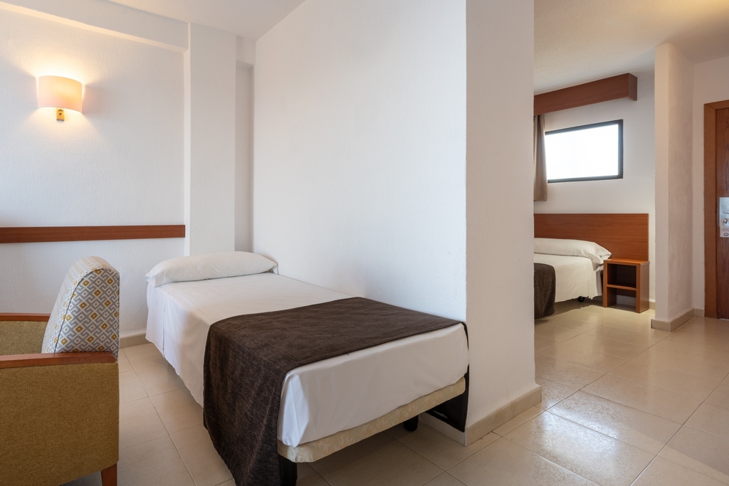 Room with two separate sleeping areas and single beds.
