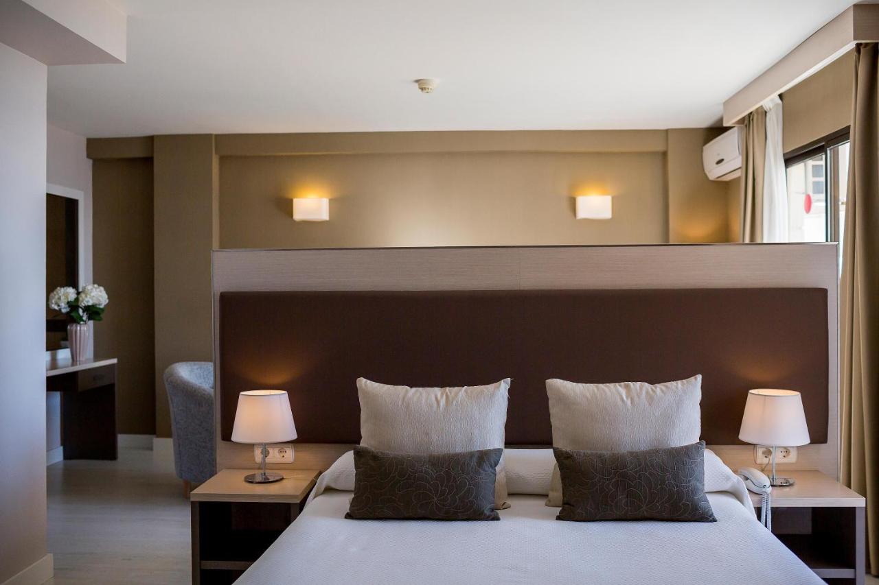 Bedroom with double bed, lamps and a divider wall leading to a seating area.