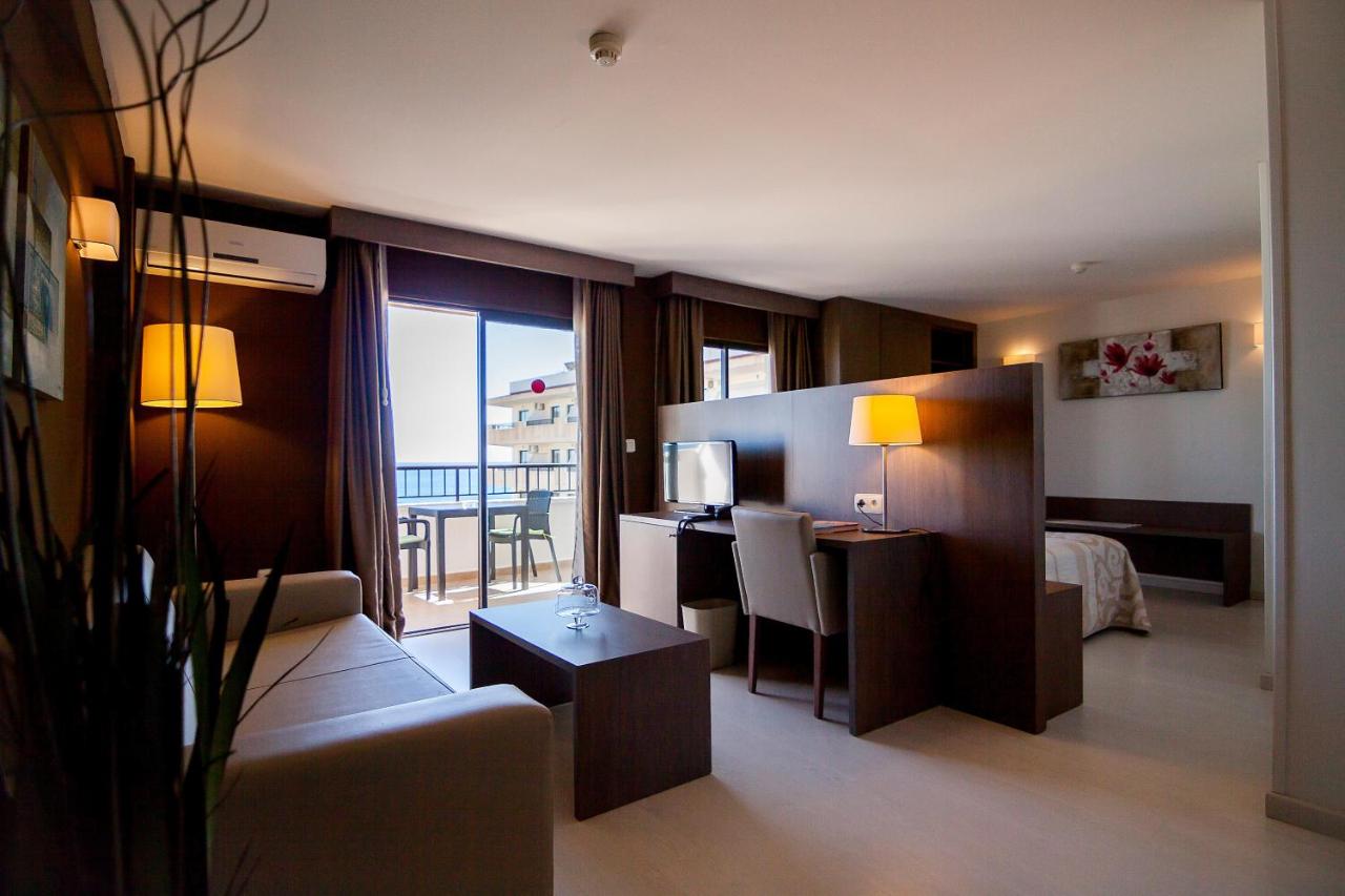 Open-plan room with sofa, desk, TV and sleeping area.