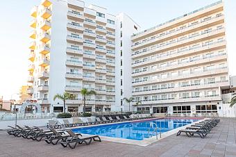 Hotel exterior with outdoor pool and sun loungers in the courtyard.