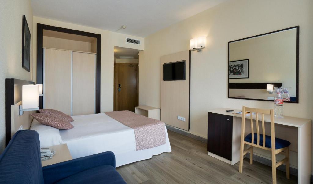 Guest room with double bed, sofa, desk, wardrobe, and wall-mounted TV.