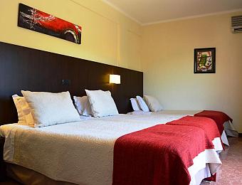 Triple room with three single beds, wall art and bedside lighting.