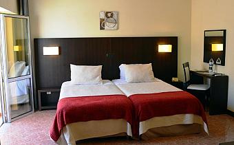 Twin room with desk, mirror and open balcony door.