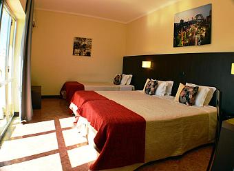 Triple room with three single beds and daylight from the balcony doors.