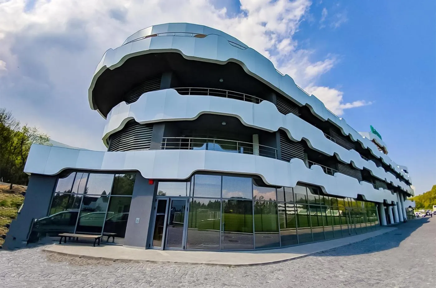 Modern multi-story hotel with curved balconies and glass facade, accommodation for teams during a sports training camp