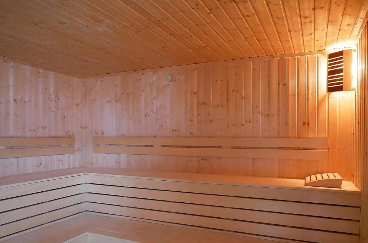 Wooden sauna with tiered benches and warm lighting, recovery facility for athletes after training sessions