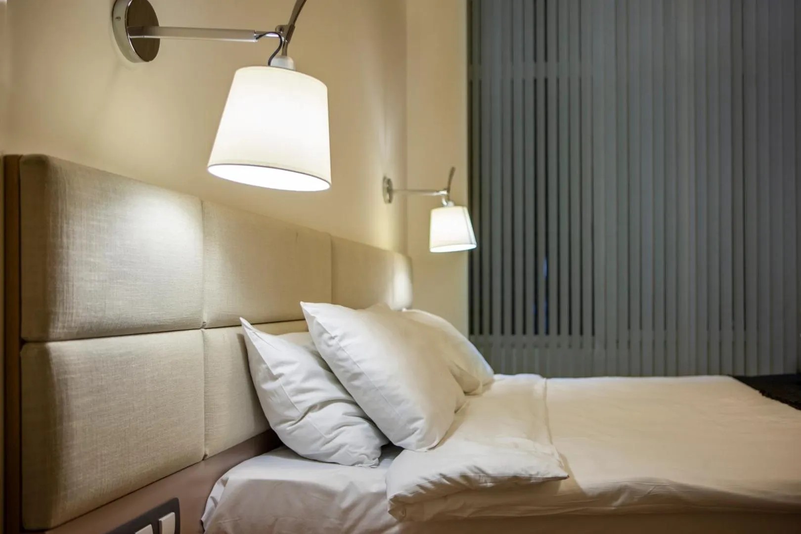 Close view of hotel bed with reading lamps and pillows, comfortable lodging for training camp athletes