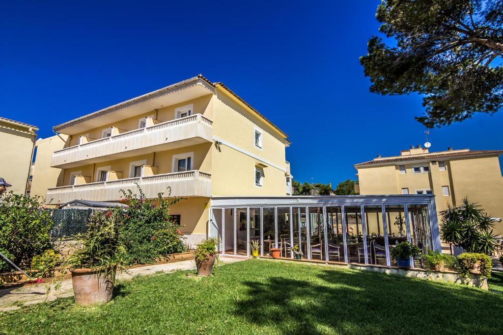 Three-story hotel exterior with garden and covered glass lounge.