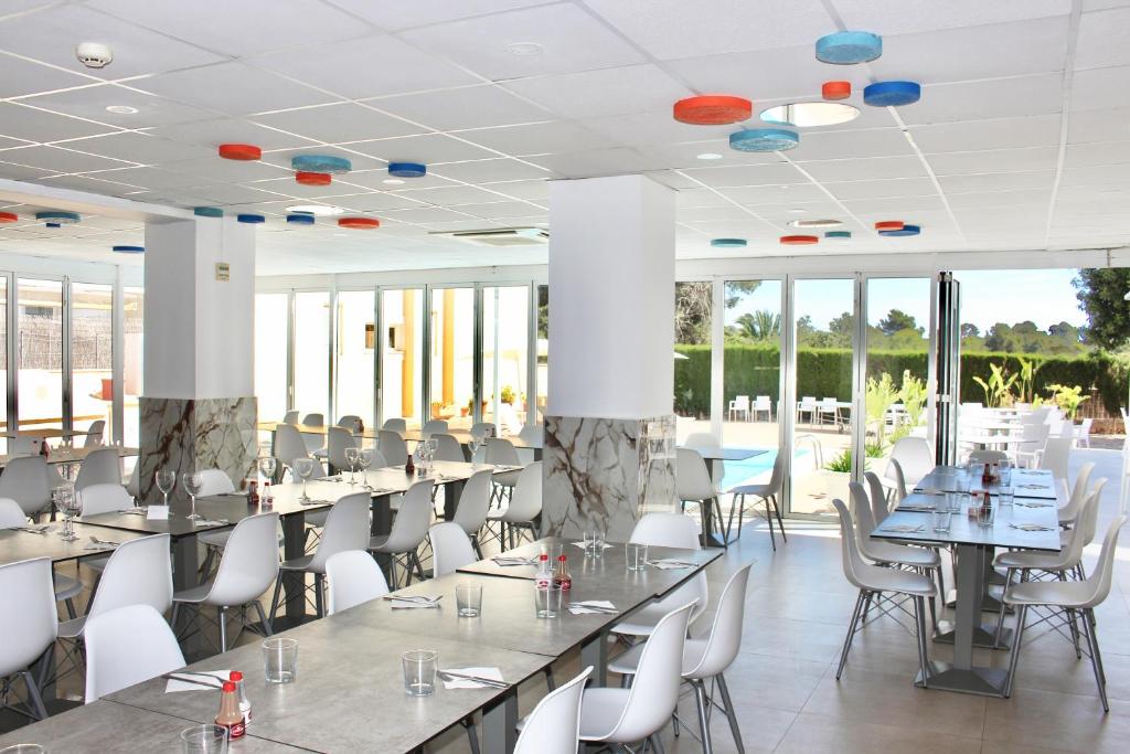Bright dining room with long tables, white chairs and large sliding doors to patio.