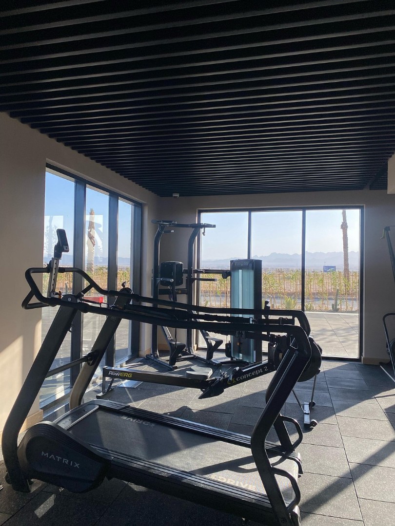 Small gym with cardio machines and large windows overlooking outdoor view