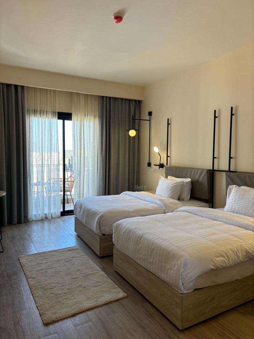 Guest room with two single beds, rug, and balcony access