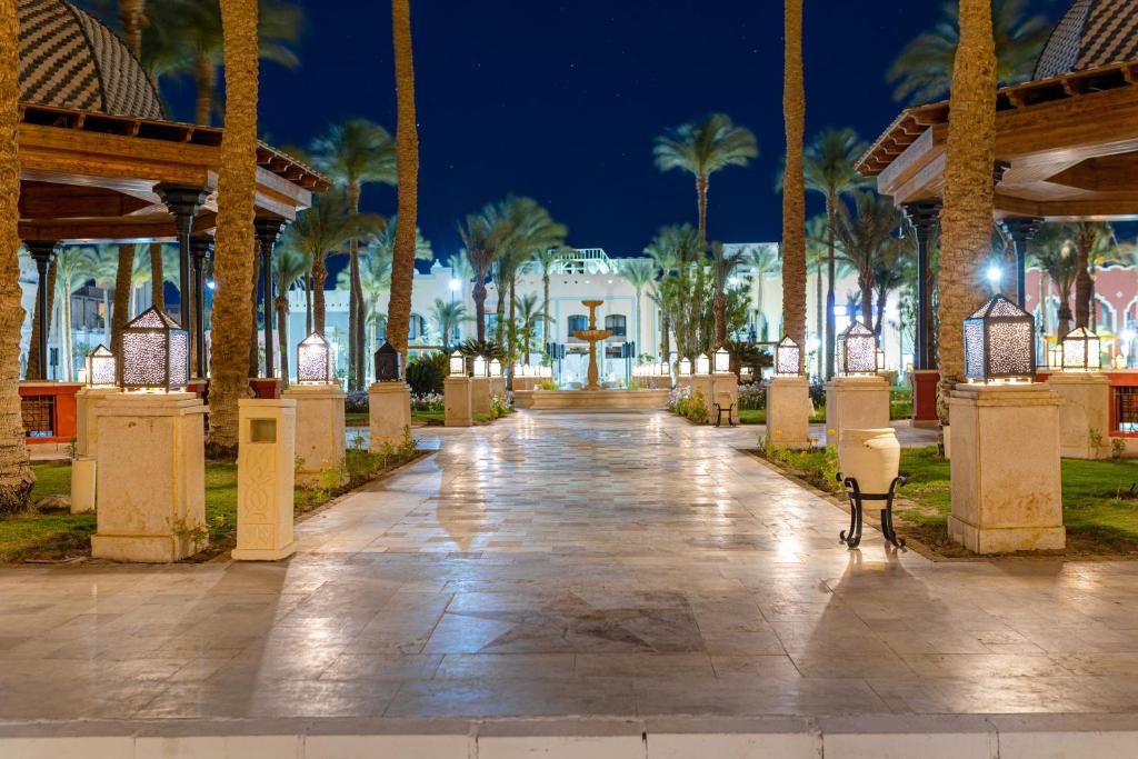 Pathway lined with palm trees and lanterns leading to resort entrance at night