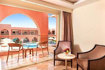 Balcony with chairs and table overlooking poolside at a resort