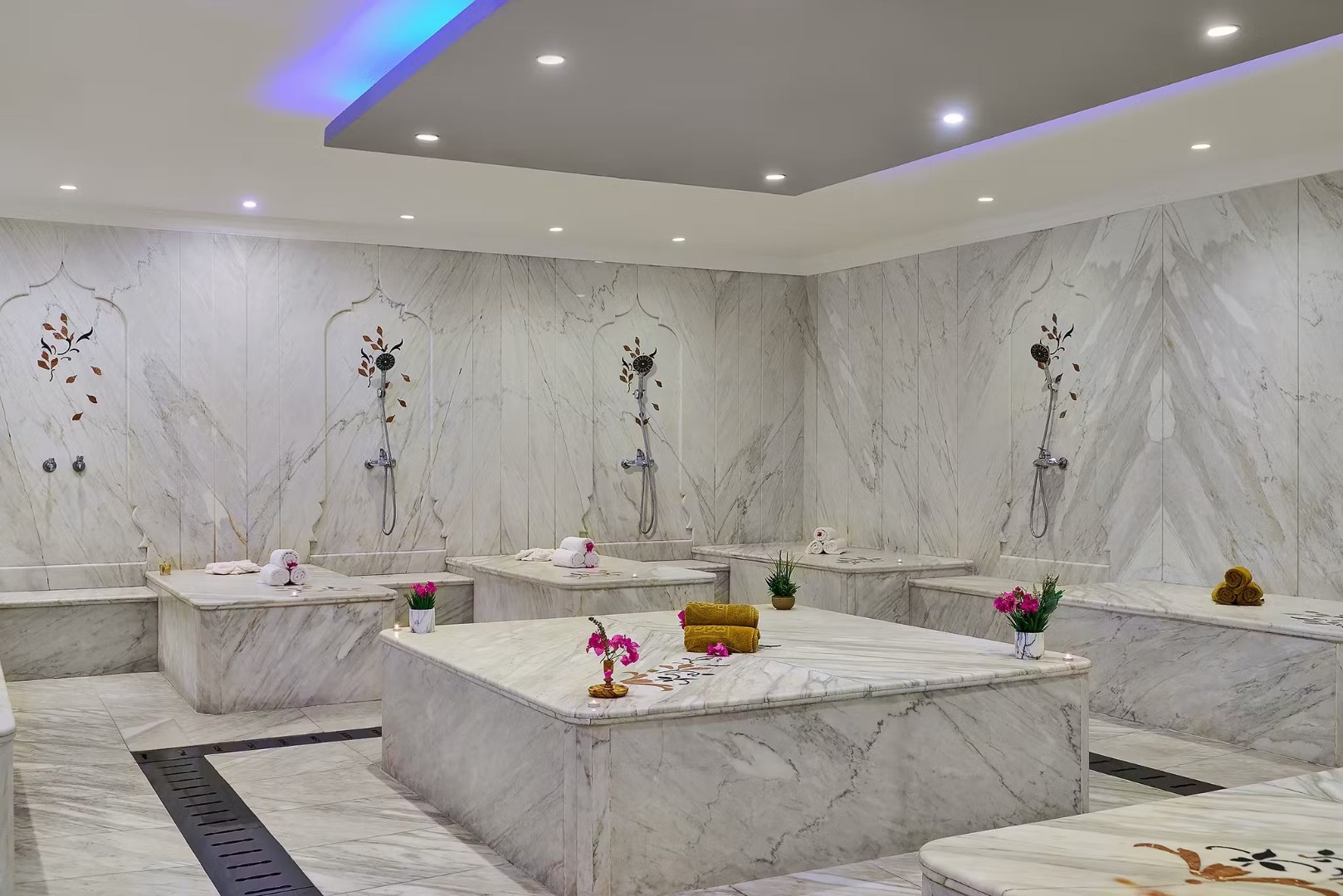 Luxurious marble spa room with massage tables and floral wall decorations