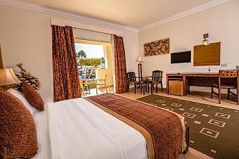 Cozy room with double bed, work desk, and pool view through sliding glass door
