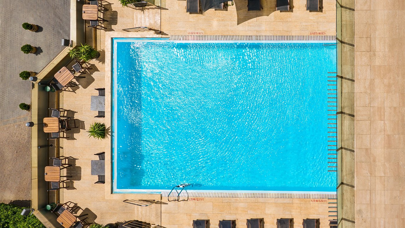 Top-down view of outdoor blue pool with deck chairs and tables for training camp recovery swim