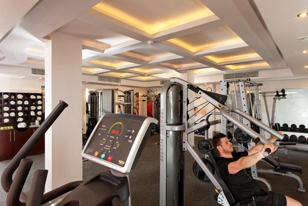 Fitness center with strength machines and dumbbells; a person training indoors.