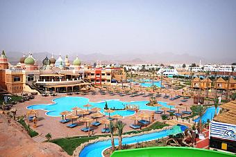 Panoramic view of resort pools and waterpark area with sun loungers and landscaped paths.