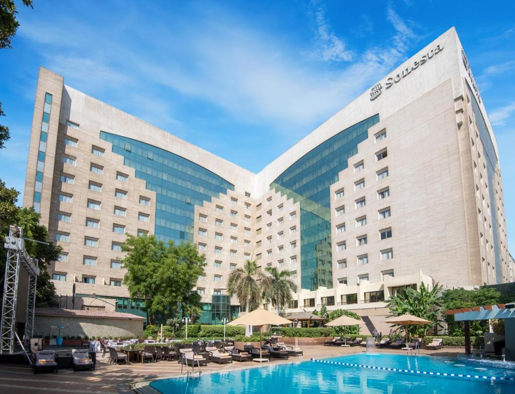 Hotel exterior with outdoor swimming pool, sun loungers, and terrace seating in the courtyard.