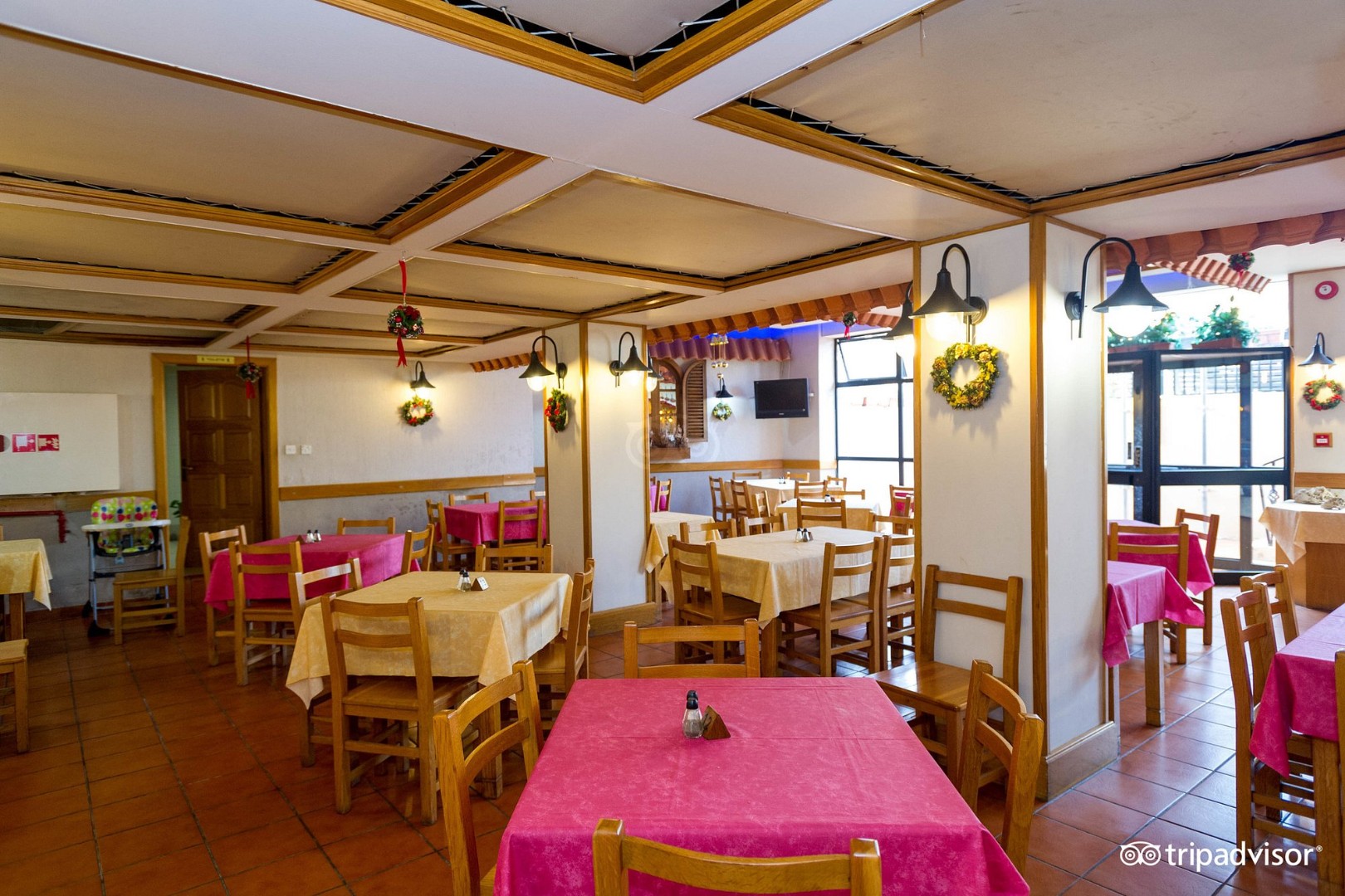 Restaurant dining room with wooden tables, chairs, and pink tablecloths.
